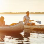4 people canoeing in a lake with the sunset over them. Retreat Essentials, concept image.