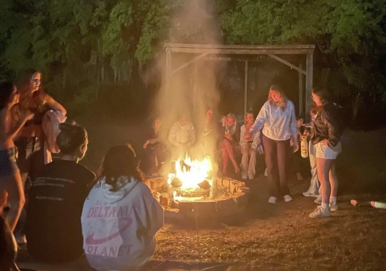 Campers and staff roasting food over an open fire pit.